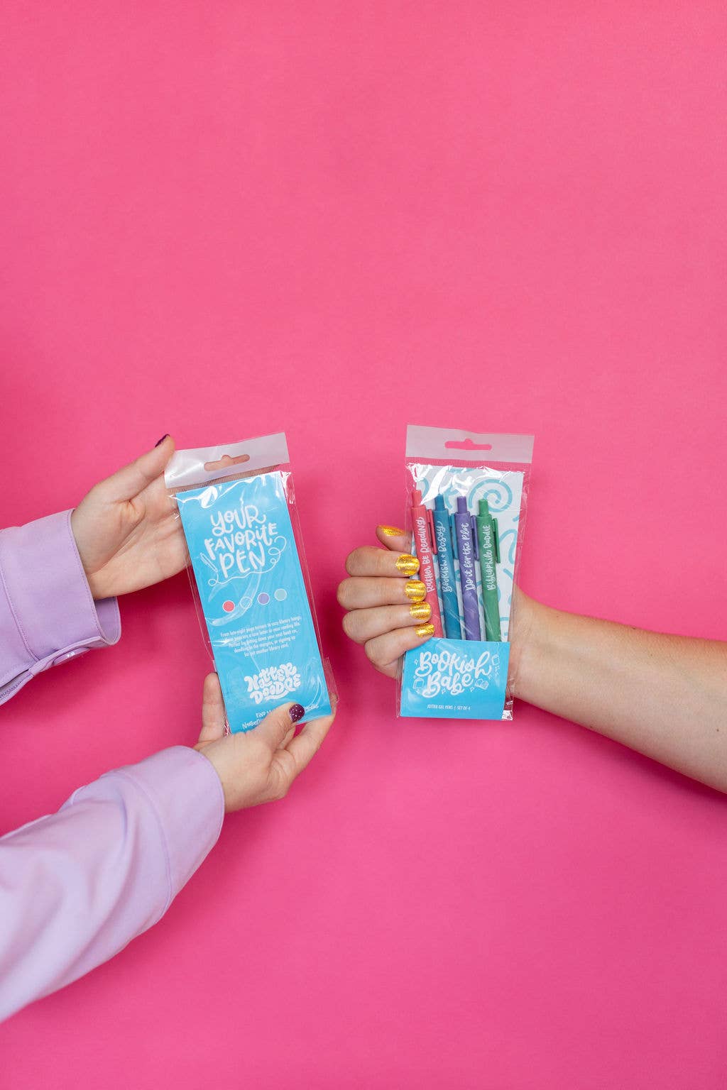 Two hands holding packages of 'Hello Kitty' products against a pink background