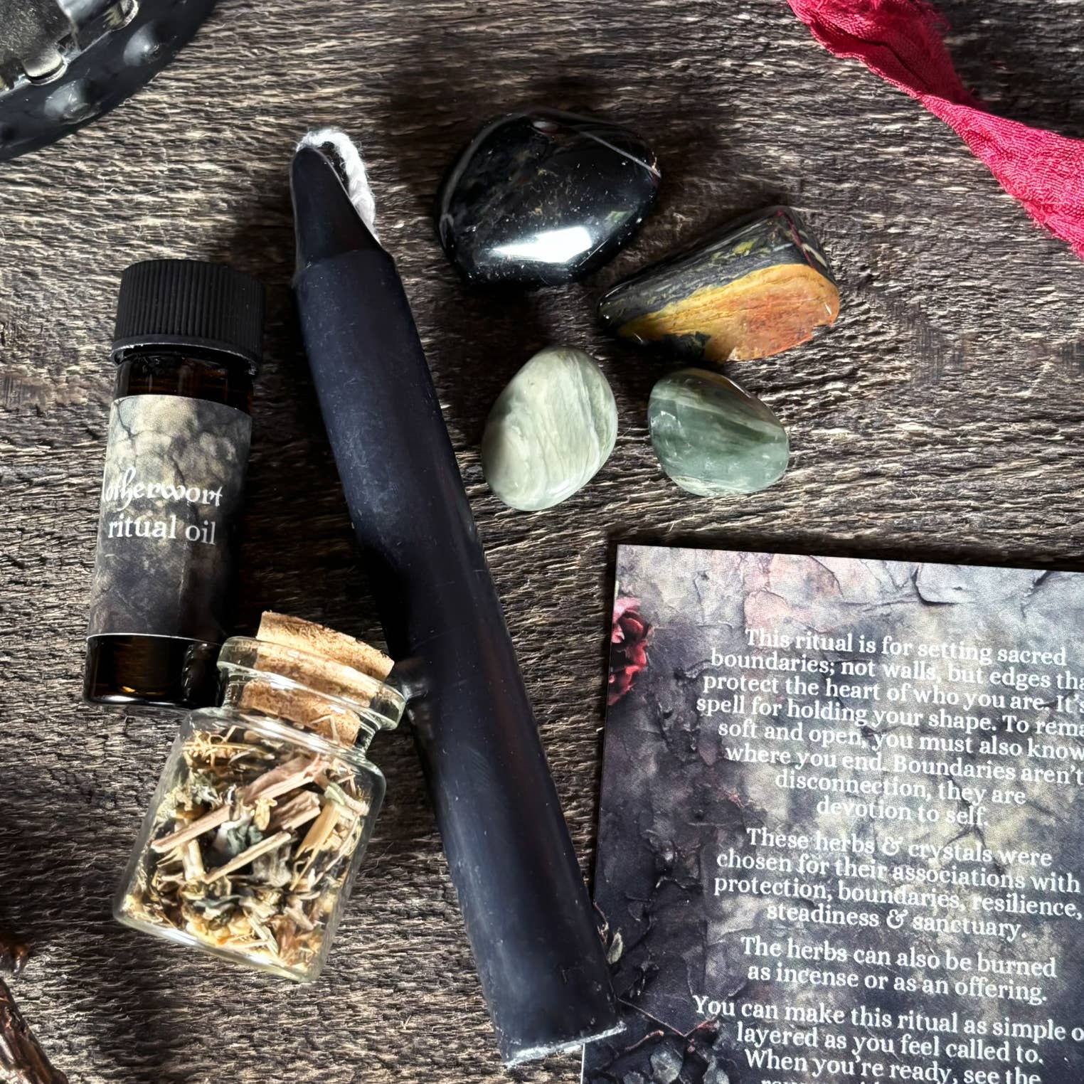 Witchcraft supplies including a bottle of oil, herbs, a knife, and stones on a wooden surface.