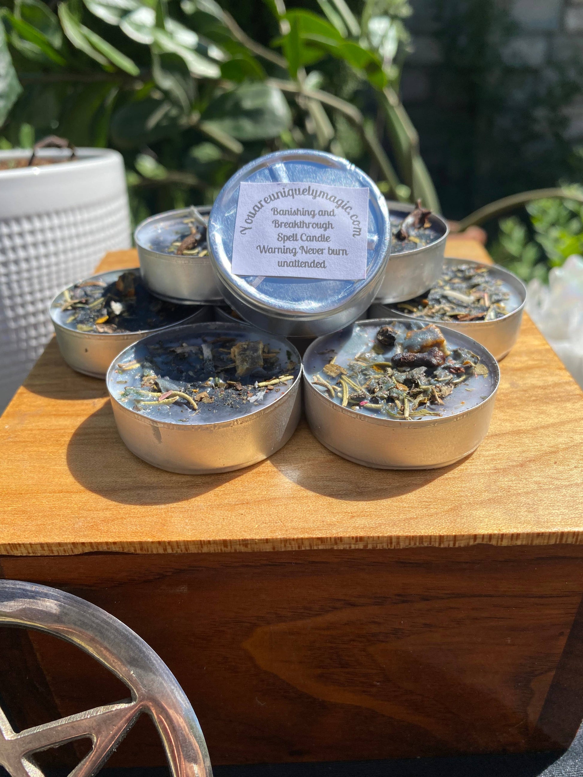 Set of small candles  on a wooden surface, surrounded by greenery.
