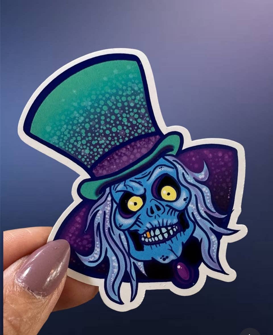 Sticker of a blue-skinned character with a top hat held against a dark background