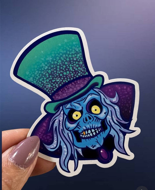Sticker of a blue-skinned character with a top hat held against a dark background