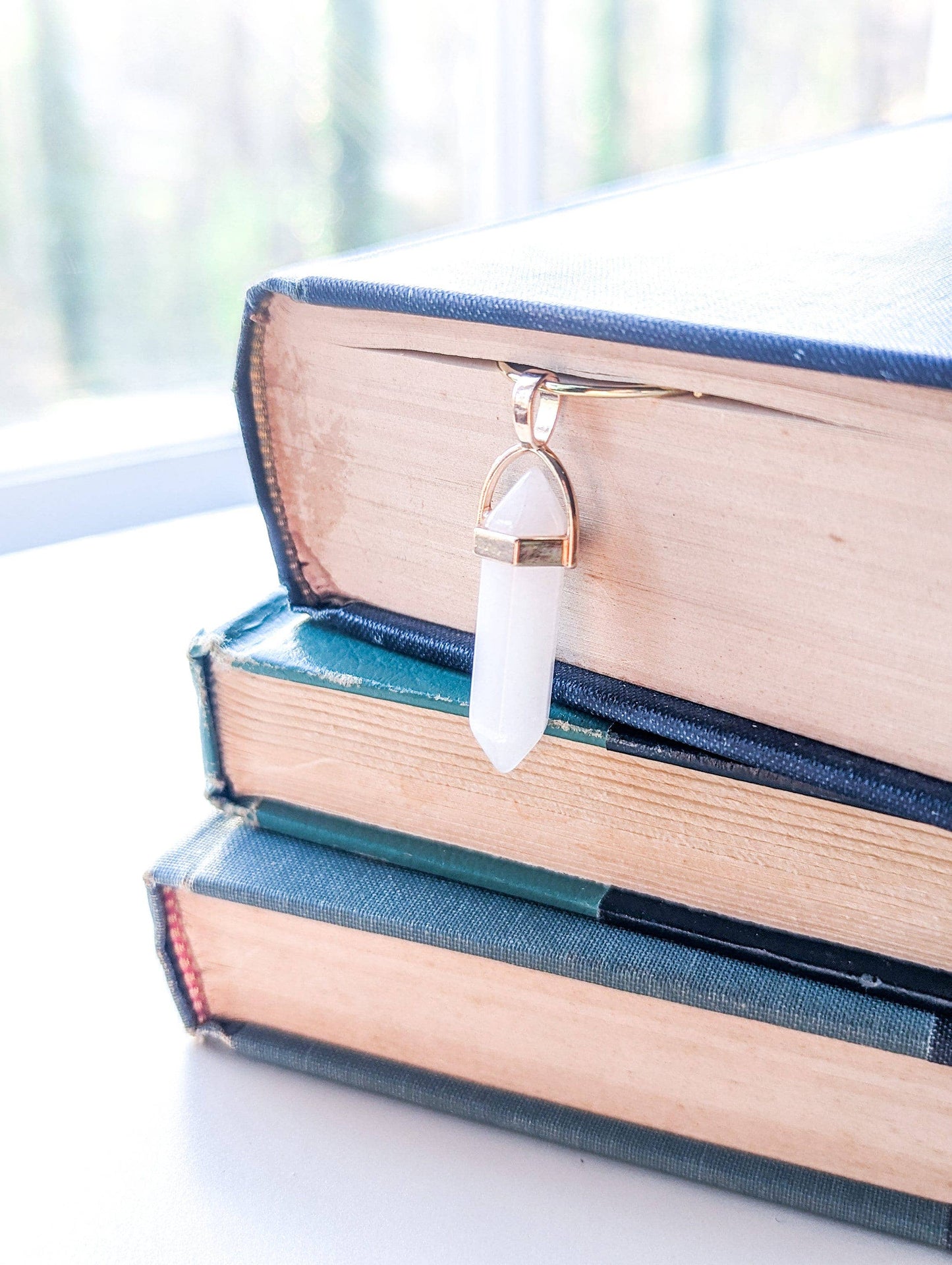 Necklace with a white pendant on a stack of books