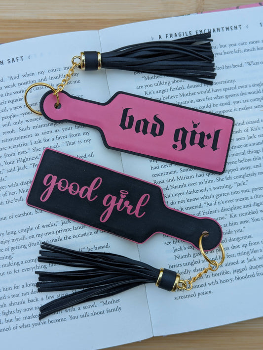 Two pink and black keychains with tassels on an open book