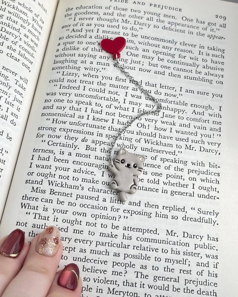 Open book with text, a cat and heart chain bookmark in the center.
