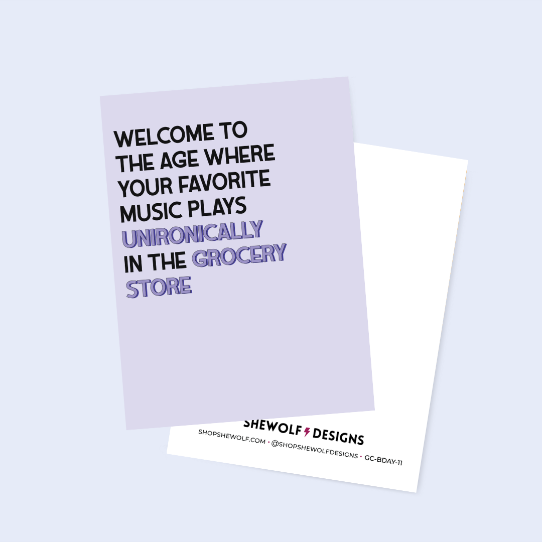 Card with humorous text about music in grocery stores on a light purple background, with Shewolf & Designs branding.