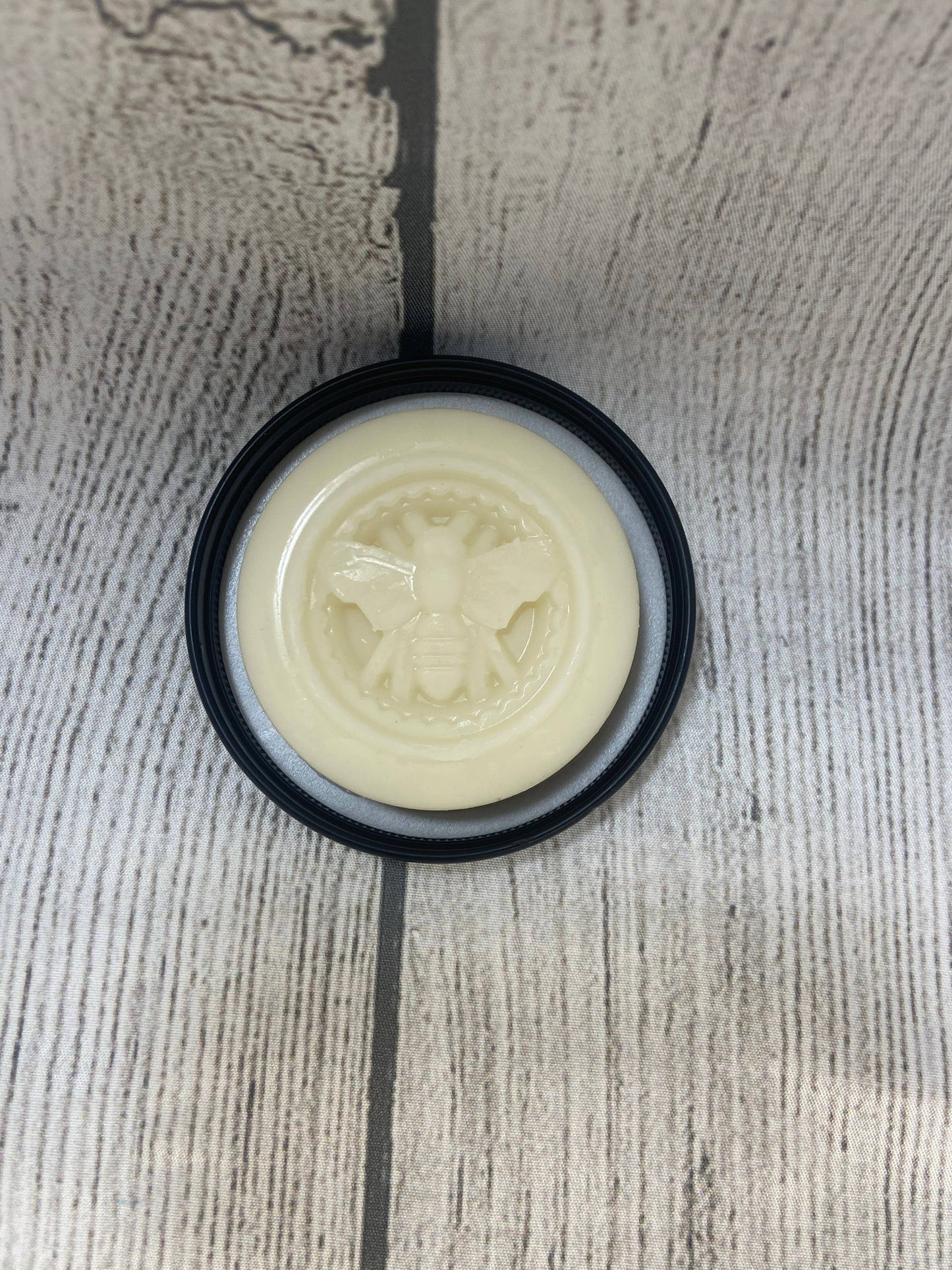 Round white object with a black rim on a textured gray surface
