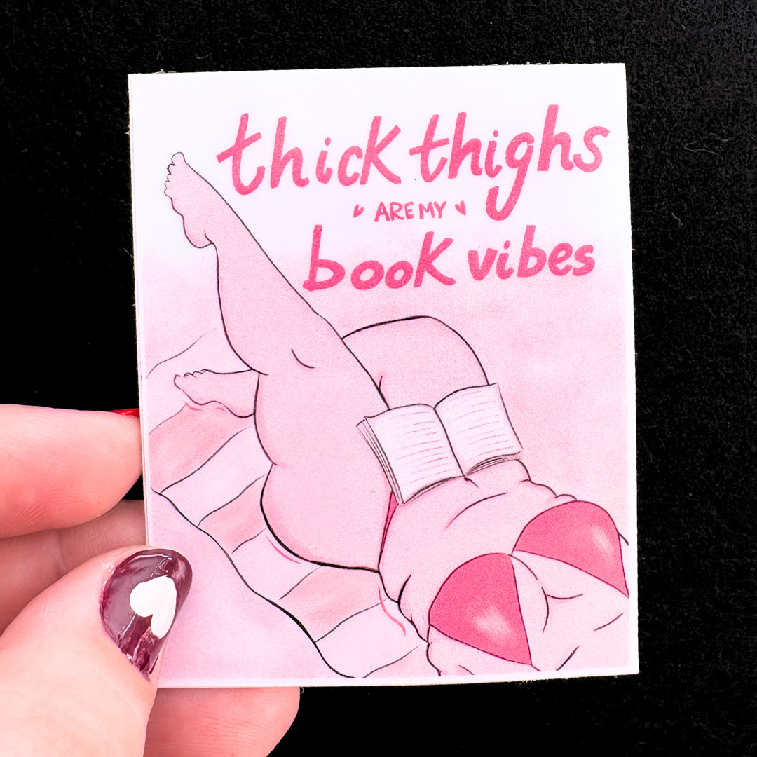 Card with illustration of legs in pink bikini holding a book, text 'thick thighs are my book vibes' on a black background.
