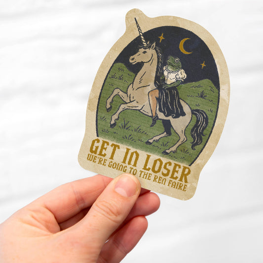 Hand holding a sticker with a unicorn and text on a white background