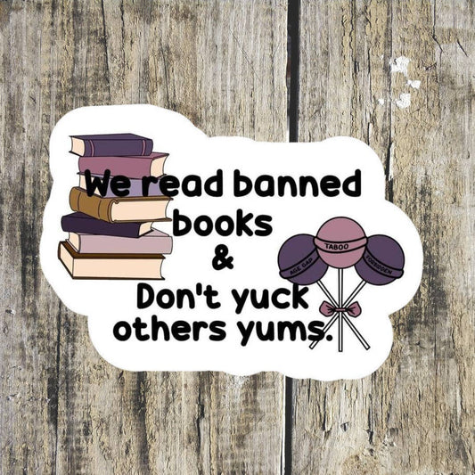 Sticker with text 'We read banned books & Don't yuck others yums.' on a wooden background