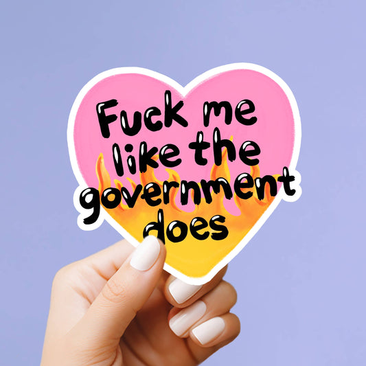 Heart-shaped sticker with offensive text held by a hand against a purple background
