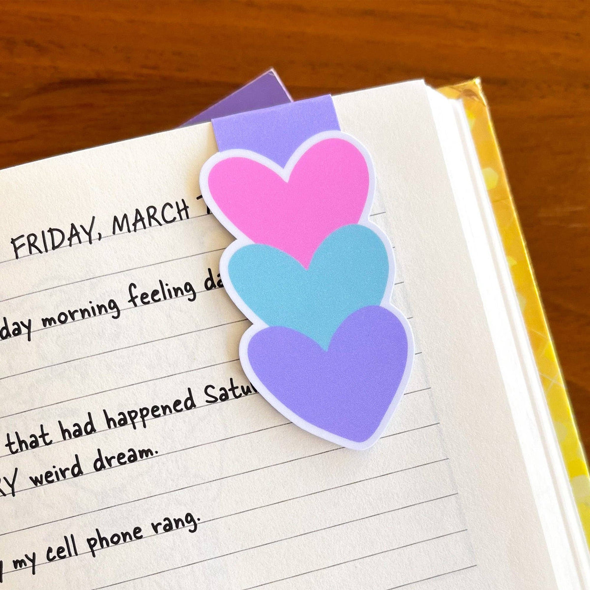 Colorful heart-shaped bookmarks on a notebook page with text.