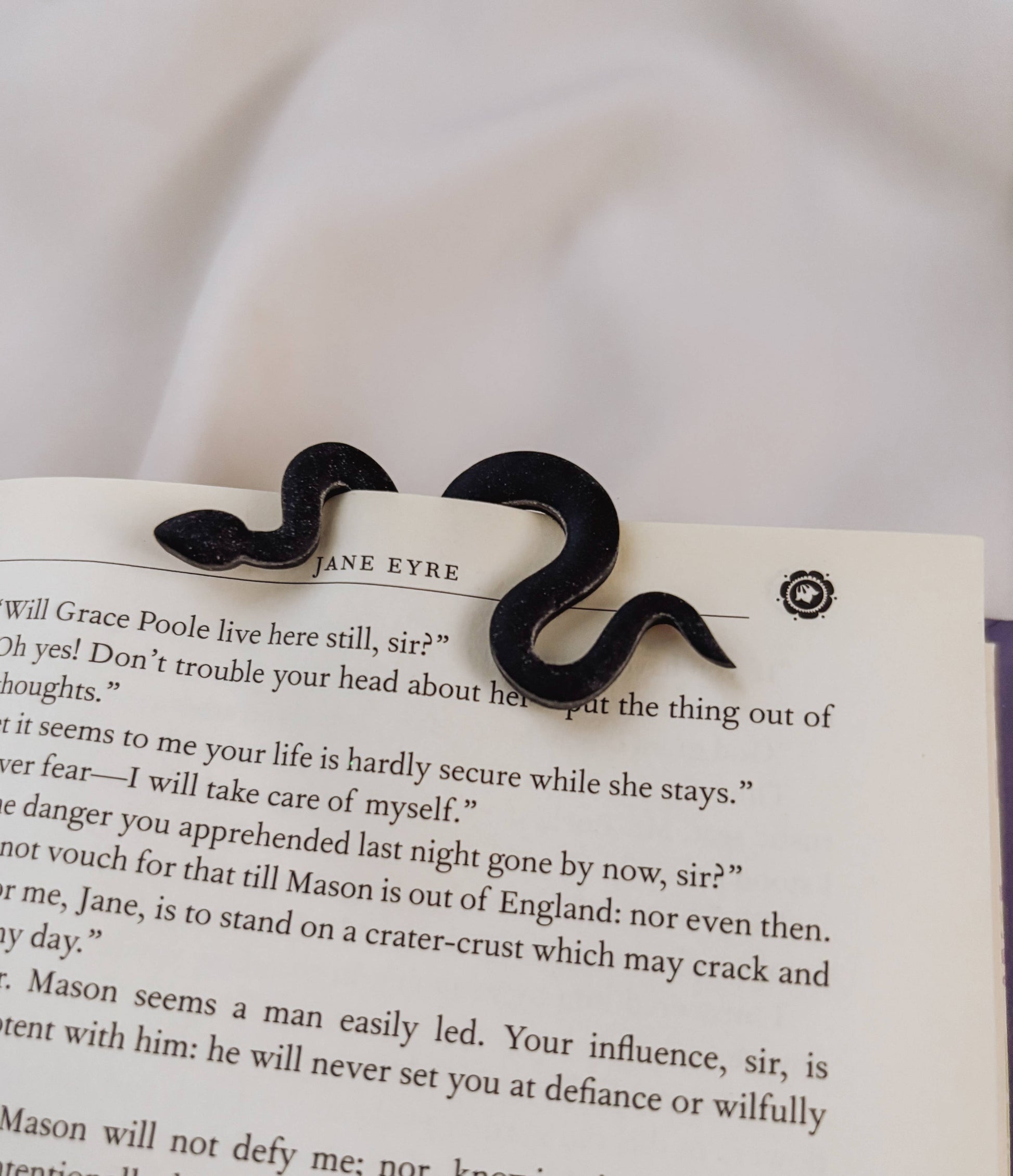 Black mustache-shaped hair clip on a page of 'Jane Eyre'