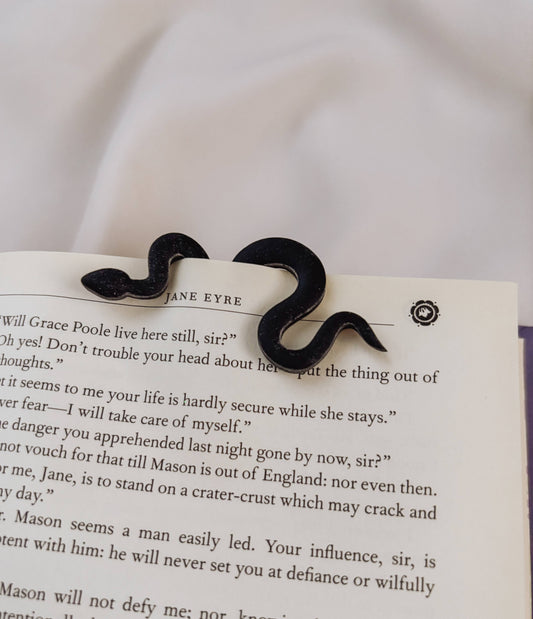 Black mustache-shaped hair clip on a page of 'Jane Eyre'