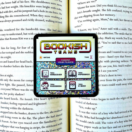 A tablet screen displaying the 'Bookish Teams' game interface, placed over an open book with printed text pages visible in the background.