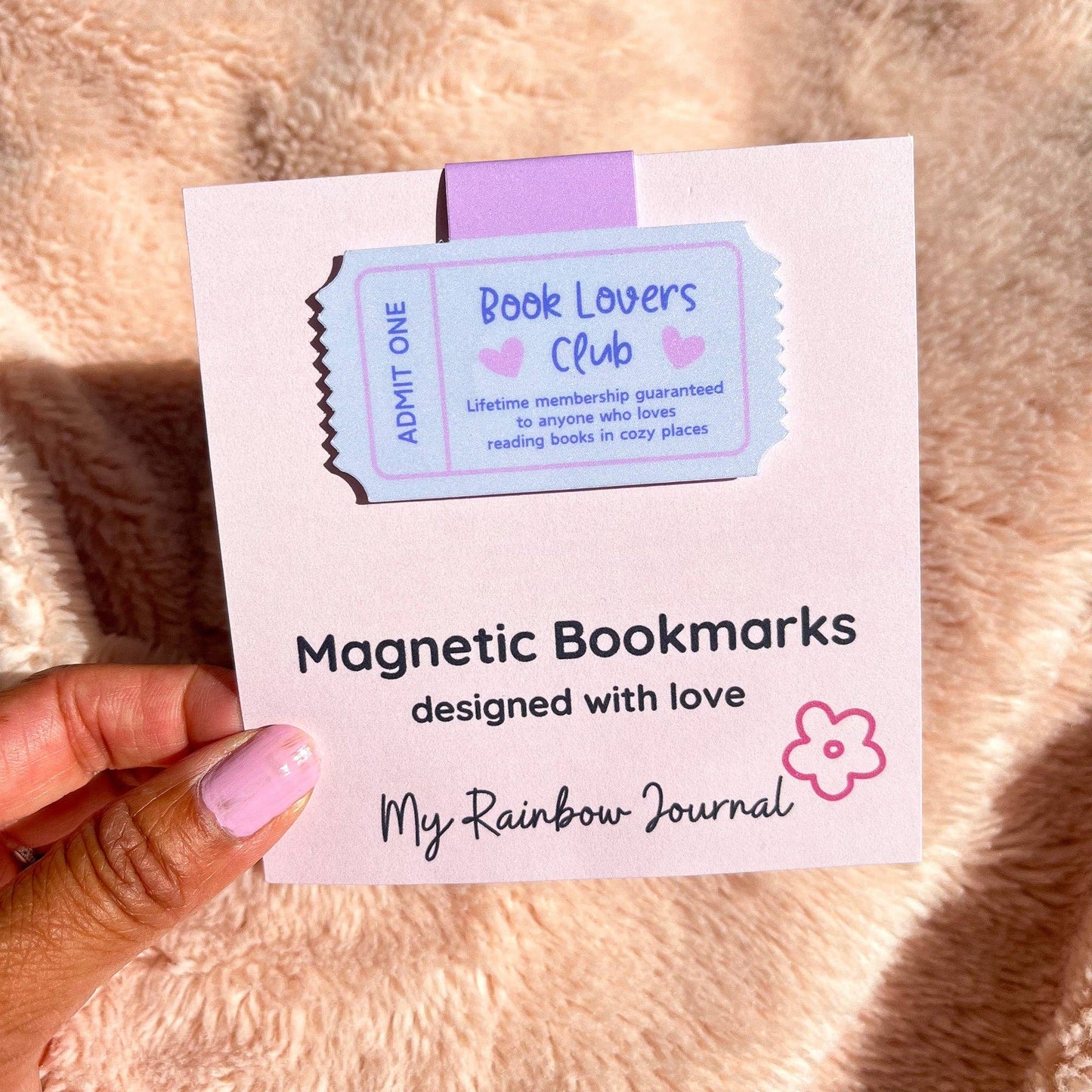 Packaging of magnetic bookmarks with a ticket design on a soft pink background