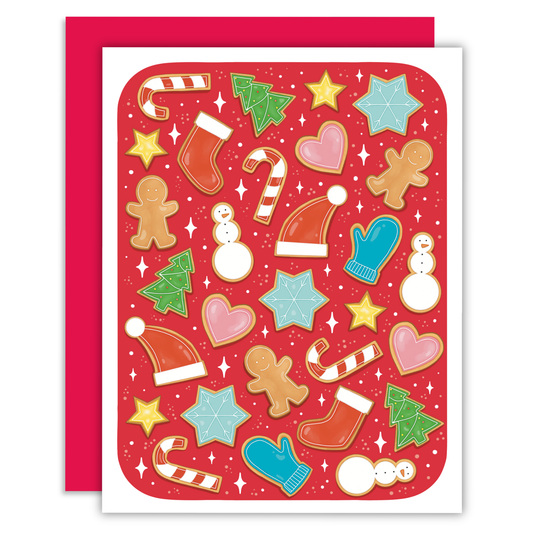 A festive Christmas card with a red background and white border, decorated with colorful holiday illustrations including gingerbread cookies, candy canes, Santa hats, mittens, snowmen, stars, and trees. A matching red envelope is placed behind the card.