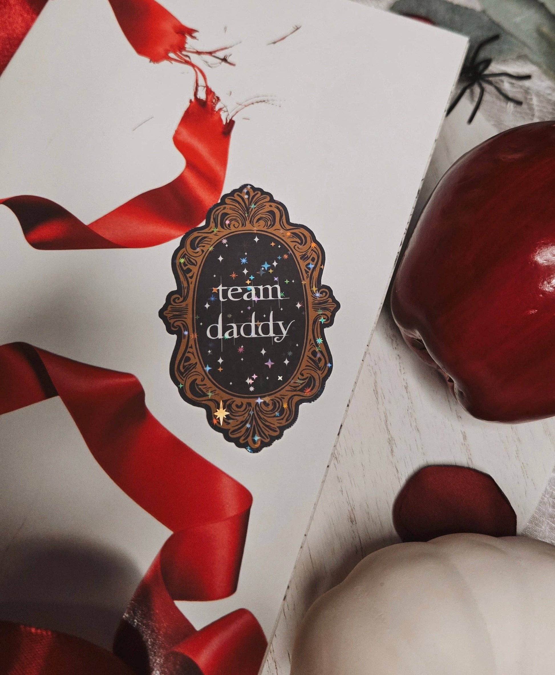 Card with 'team daddy' design and red ribbons on a textured surface