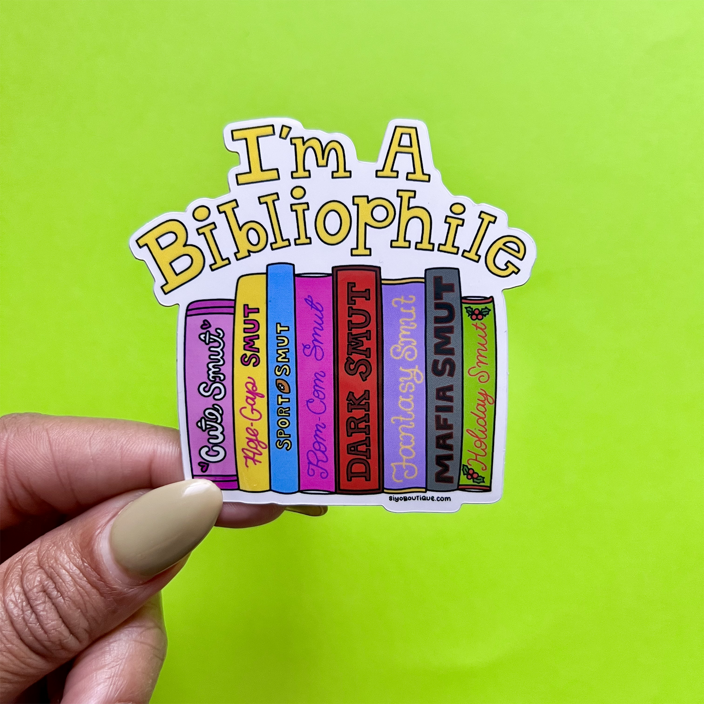 Sticker with book spines and 'I'm a Bibliophile' text held against a green background