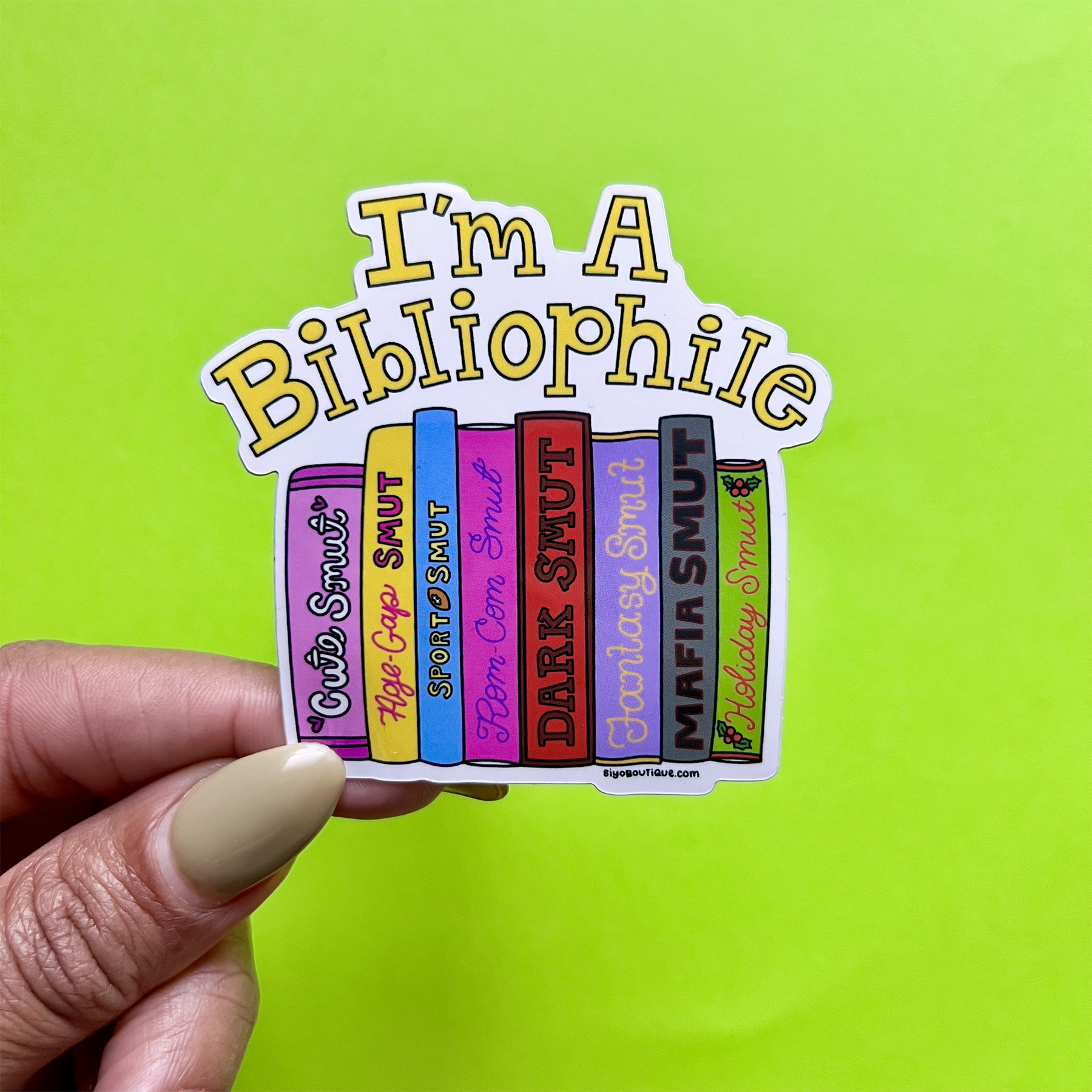 Sticker with book spines and 'I'm a Bibliophile' text held against a green background