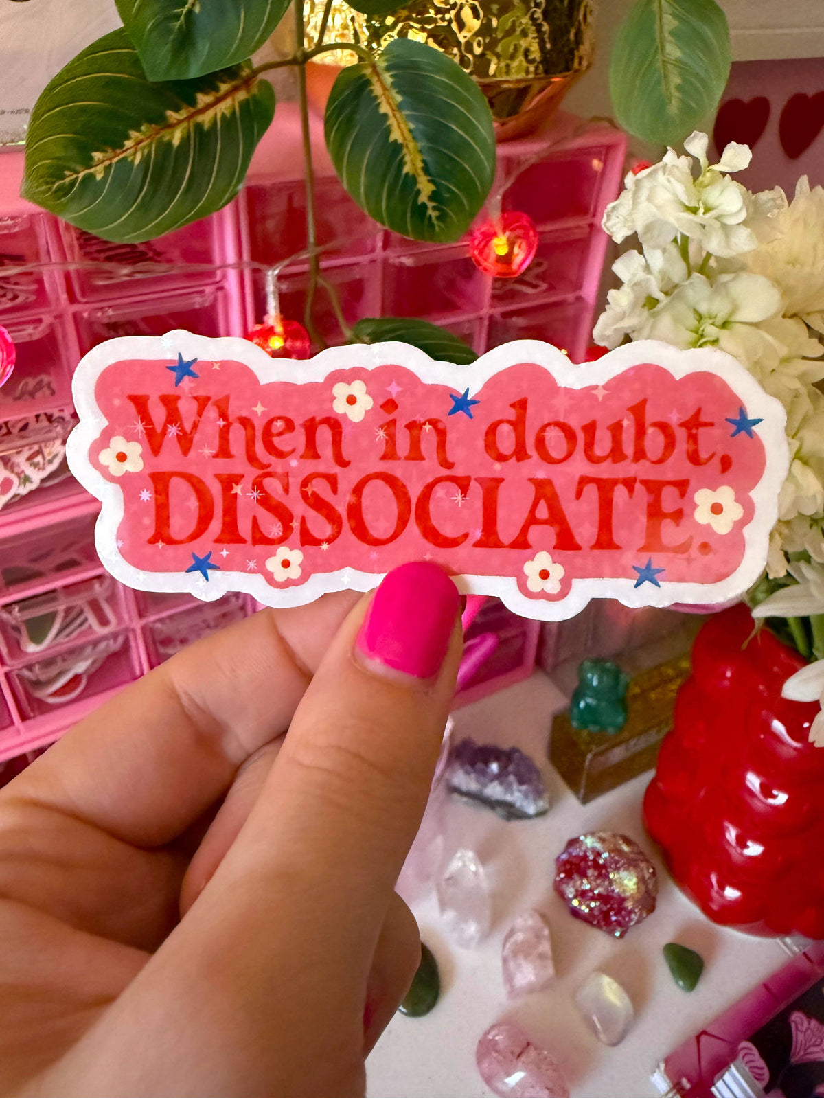 Hand holding a pink sticker with text 'When in doubt, dissociate' against a colorful background.
