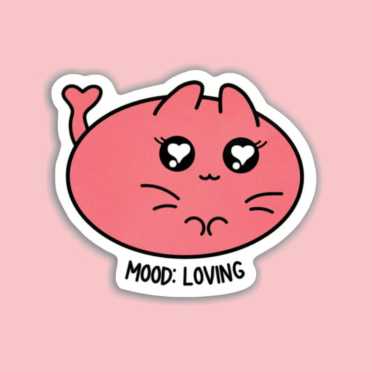 A die-cut sticker featuring a cute pink cartoon cat face with heart-shaped eyes and the text 'MOOD: LOVING' on a white background, shown against a solid pink backdrop.