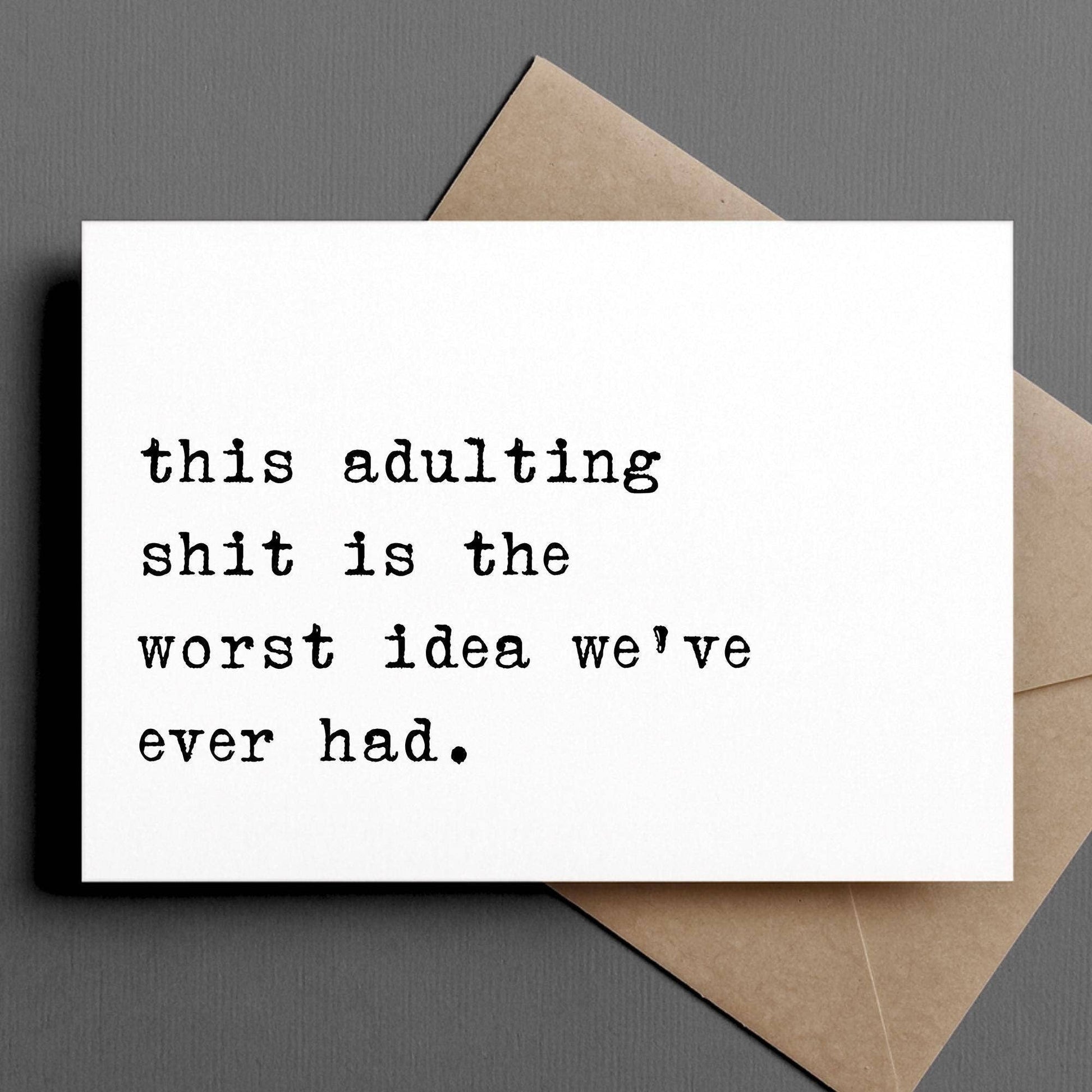 Card with humorous text 'this adulting shit is the worst idea we've ever had' on a gray background