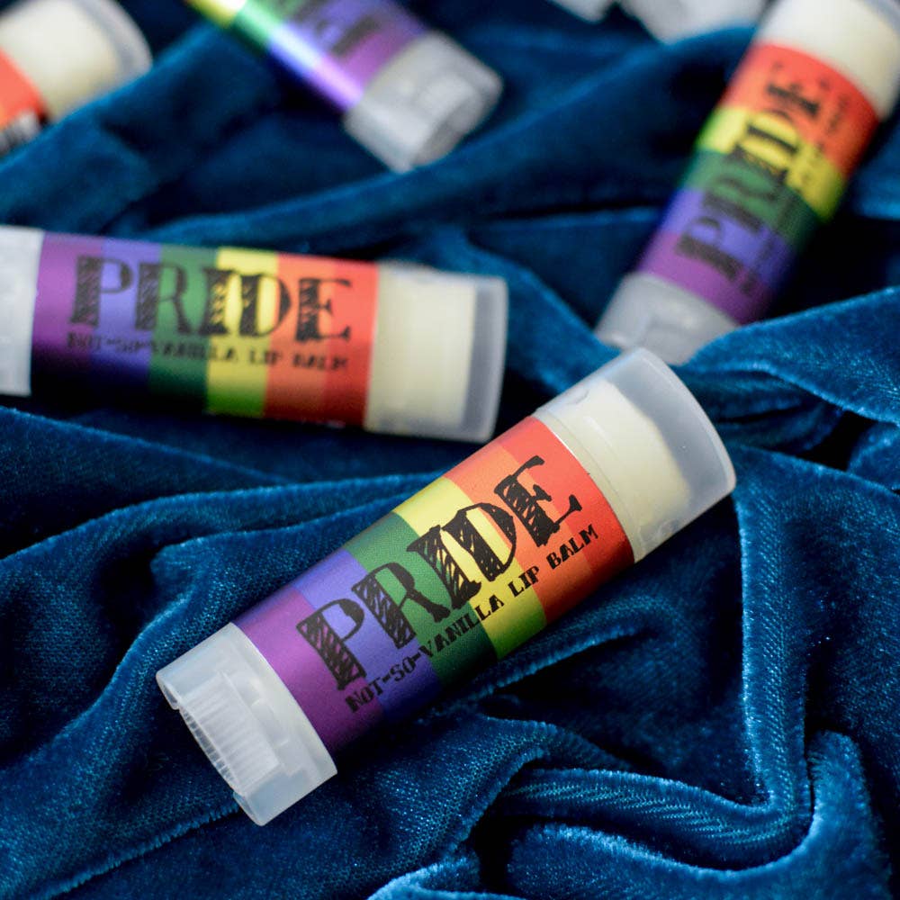 Lip balm sticks with Pride-themed labels on a blue fabric background
