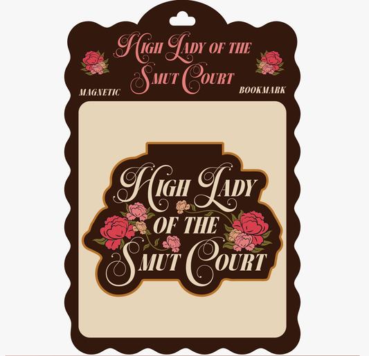 A decorative magnetic bookmark card with the phrase “High Lady of the Smut Court” in pink script and floral illustrations, shown on a plain light background.