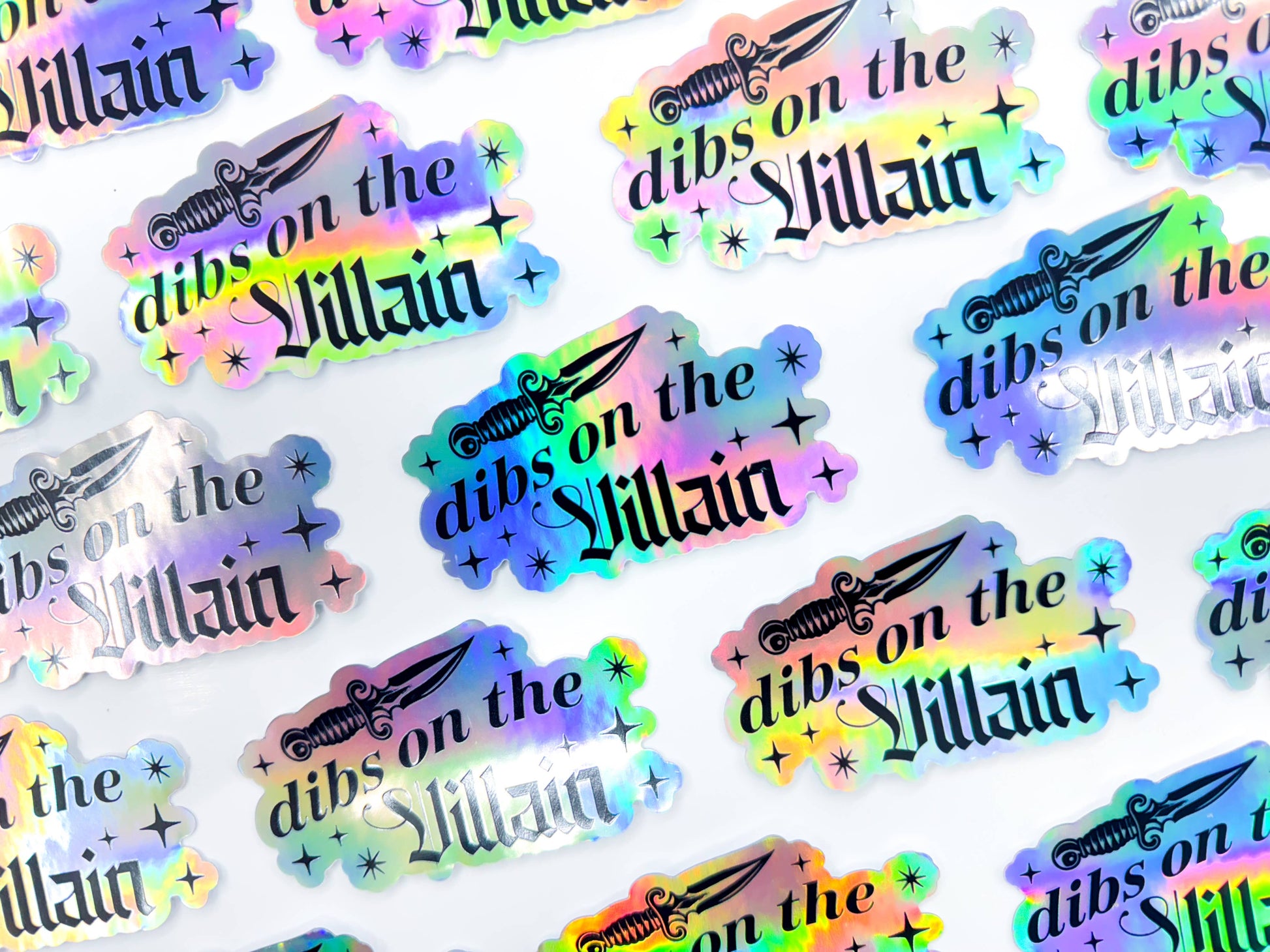 Stickers with 'dibs on the Villain' text and weapon graphics in multicolors on a white background.