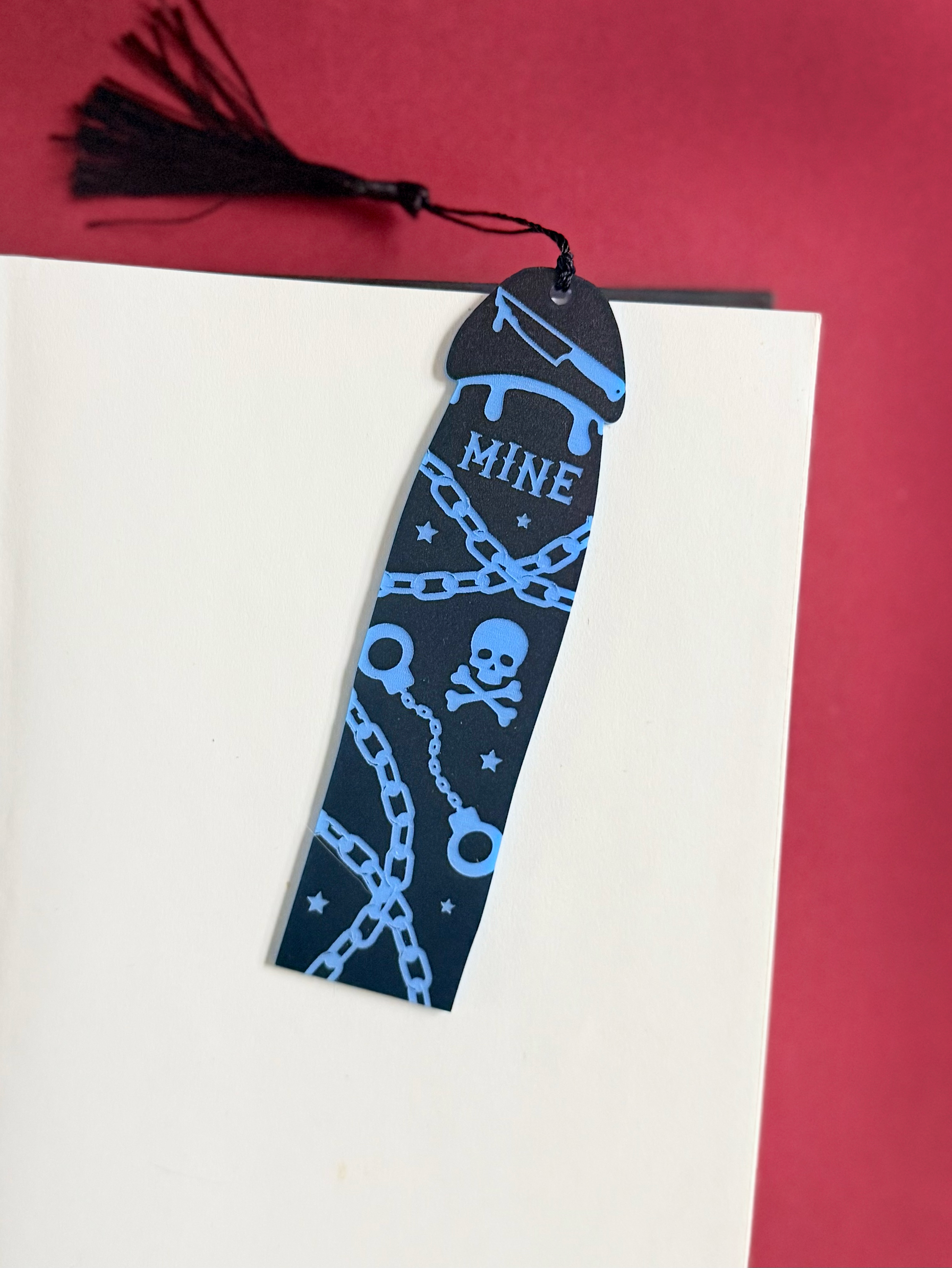 Black bookmark with blue designs and 'MINE' text on a red and white background