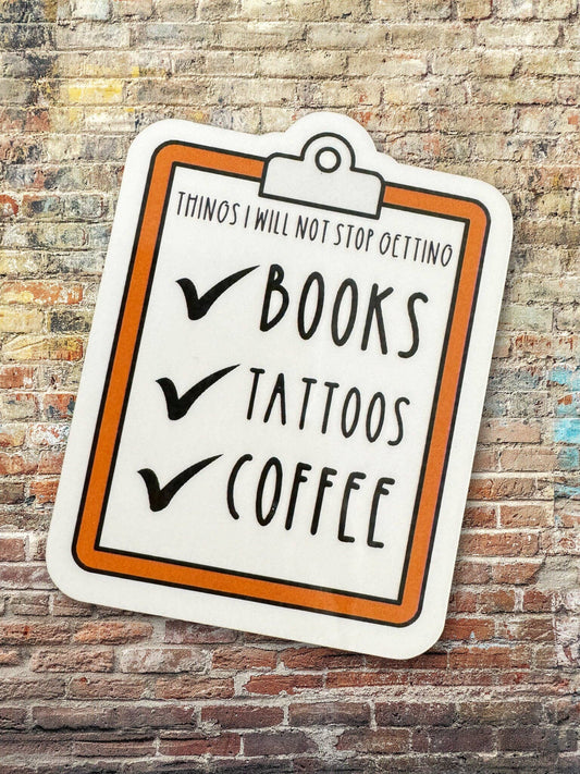 Sticker with 'Books, Tattoos, Coffee' text on a brick wall background
