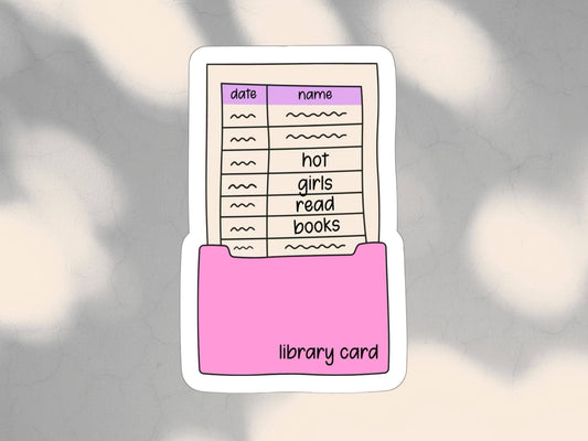 A die-cut sticker featuring a pink folder holding a cream-colored library card with a purple header and handwritten-style entries, shown on a soft gray background with blurred light patches.