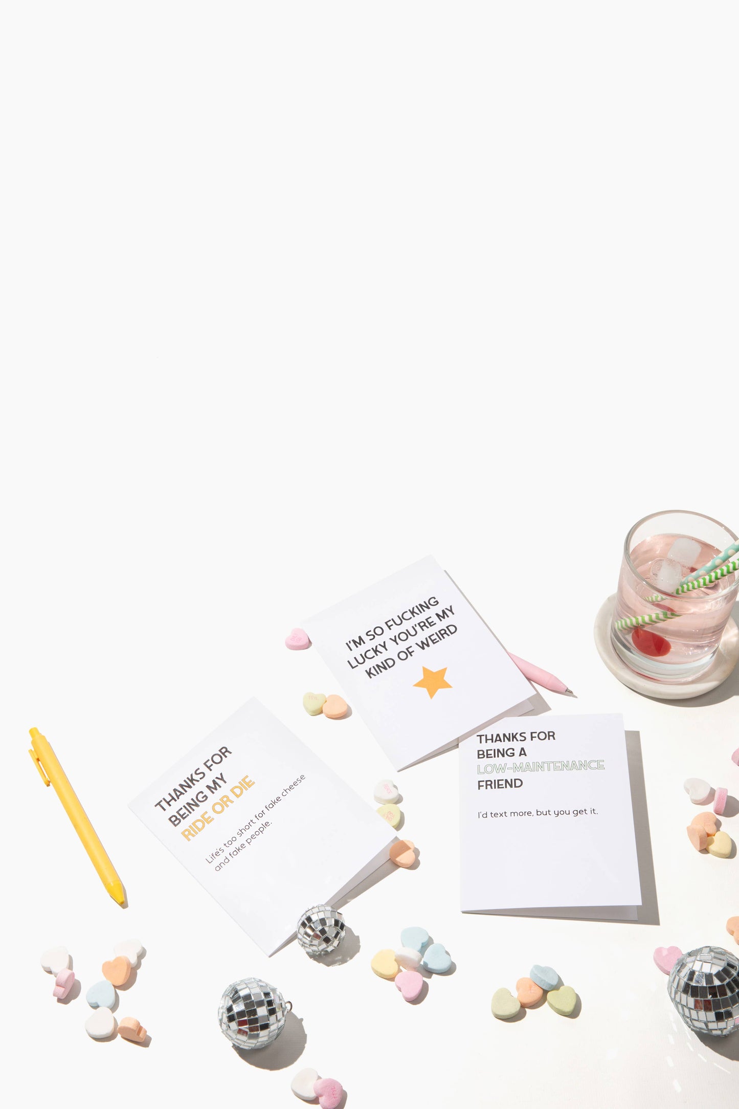 Greeting cards with text on a white surface with candies and a pen.