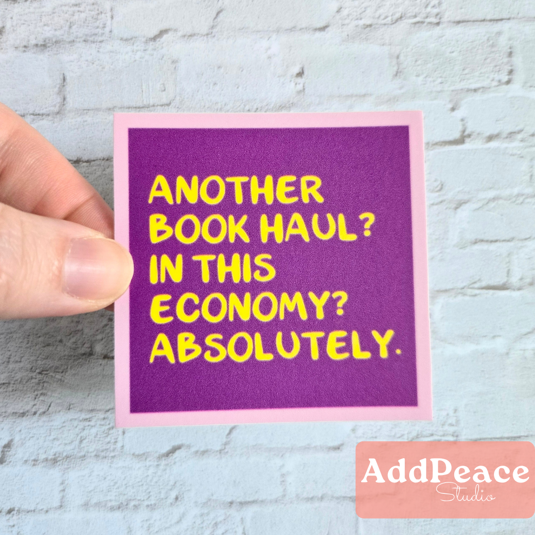 Hand holding a purple card with yellow text on a light gray brick wall background, featuring the brand 'AddPeace Studios'.