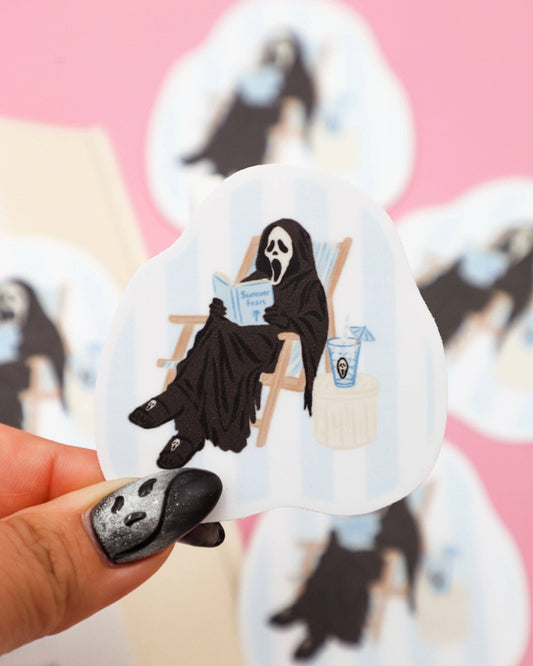 Sticker of a ghostly figure with a book and a candle held by a hand with painted nails.