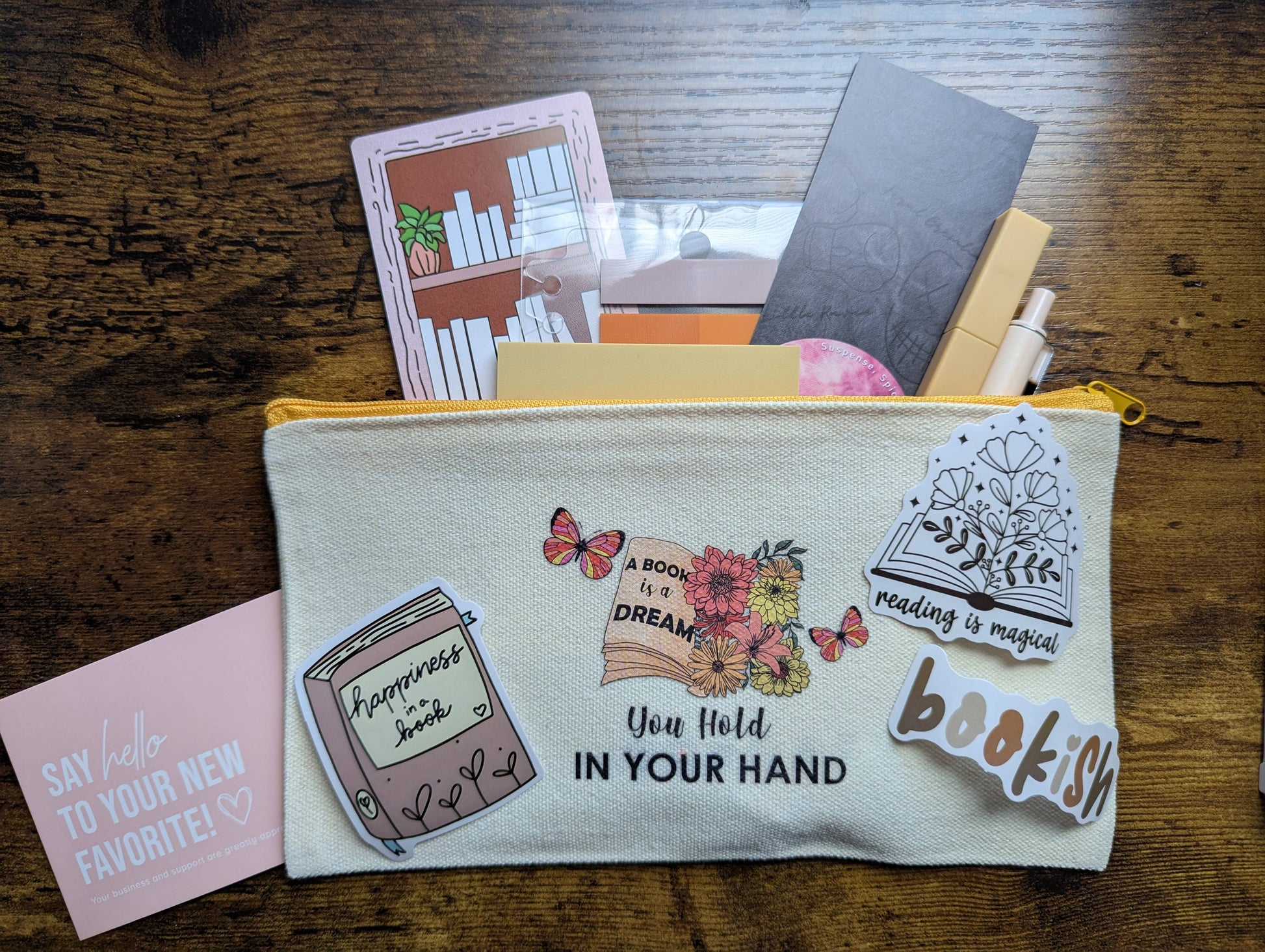 Fabric pouch with book-themed designs on a wooden surface