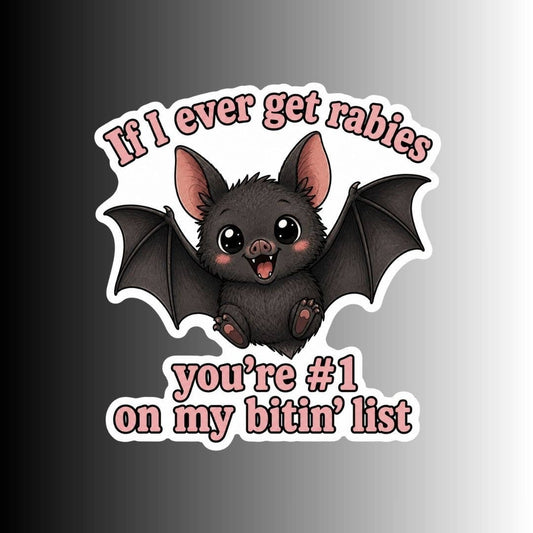 A die-cut sticker featuring a cute cartoon bat with outstretched wings and the text 'If I ever get rabies you're #1 on my bitin' list' in pink lettering, shown on a dark-to-light gray gradient background.