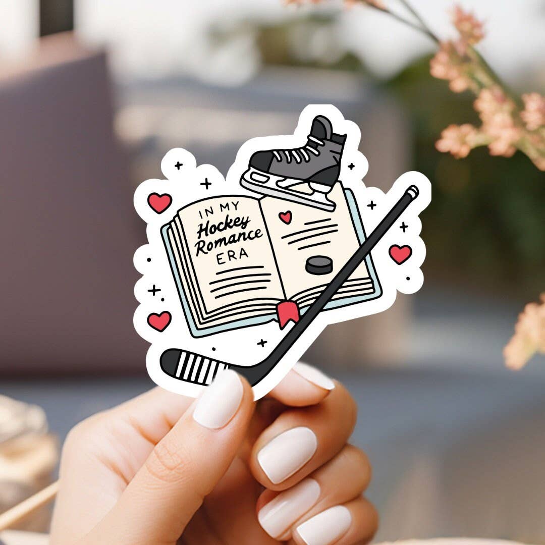 Hand holding a sticker with a book and hockey elements, text 'In My Hockey Romance Era'.