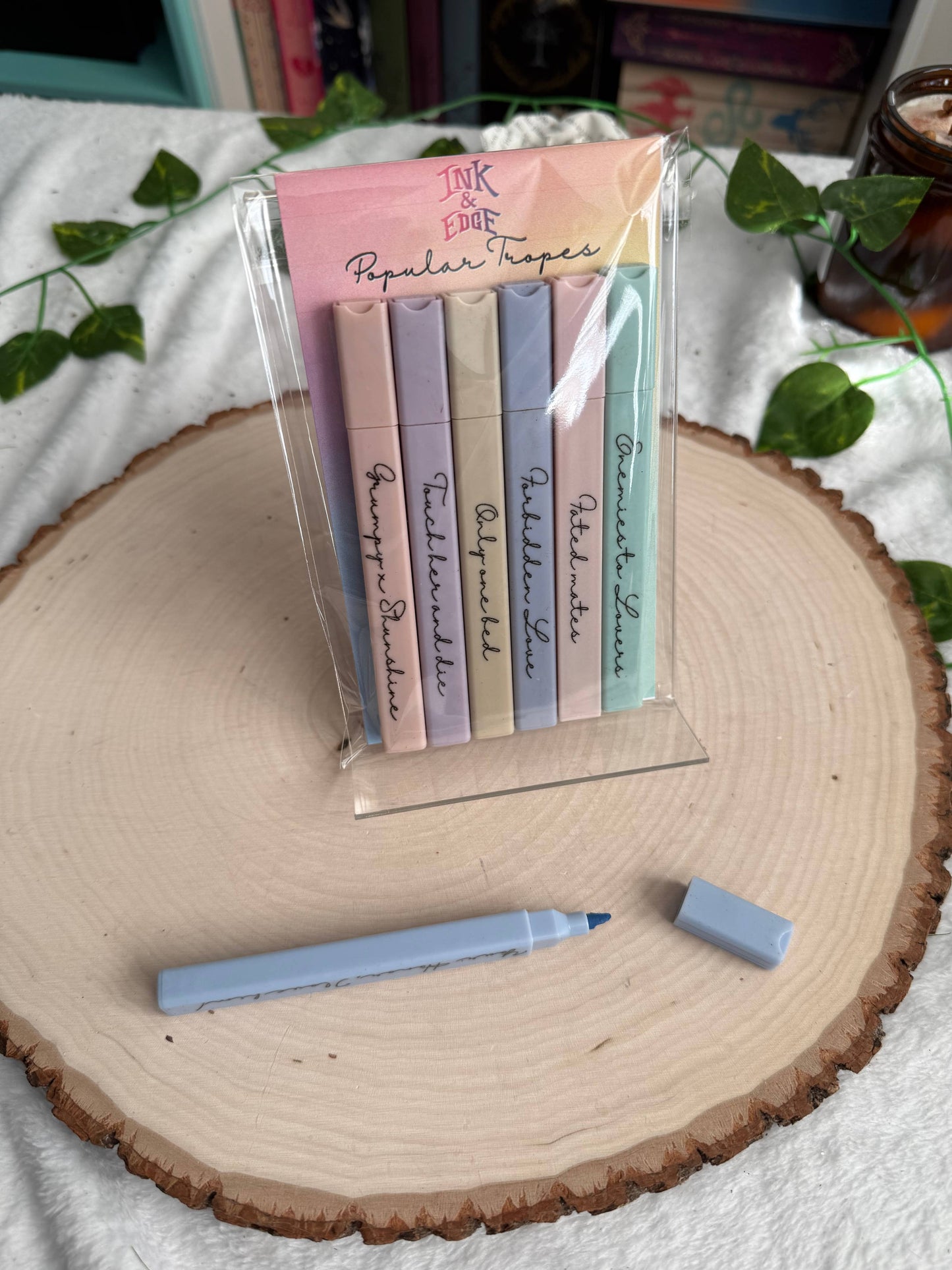 Set of pastel-colored markers with a clear stand on a wooden surface.