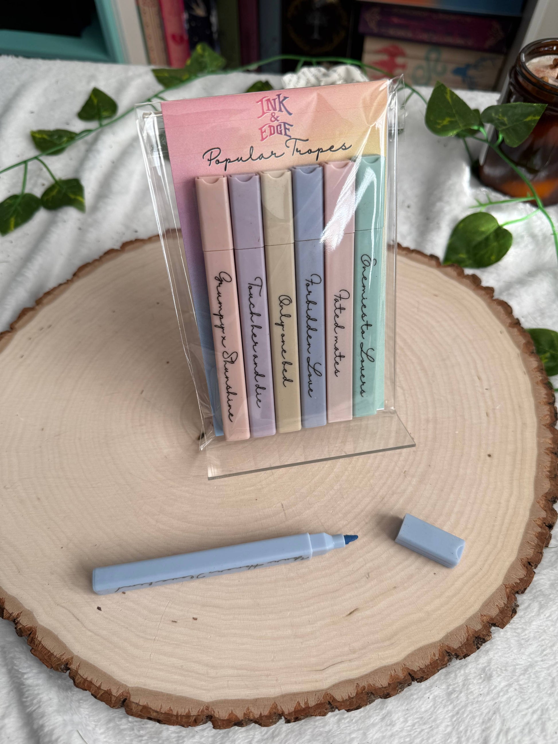 Set of pastel-colored markers with a clear stand on a wooden surface.