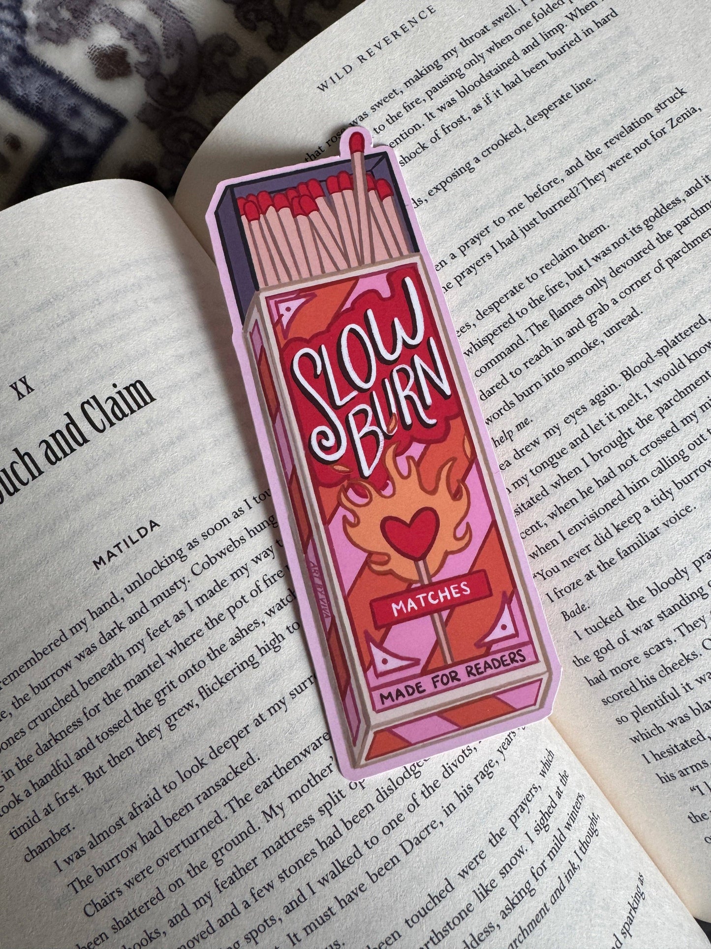 Bookmark shaped like a matchbox with 'Slow Burn Matches' design on an open book.