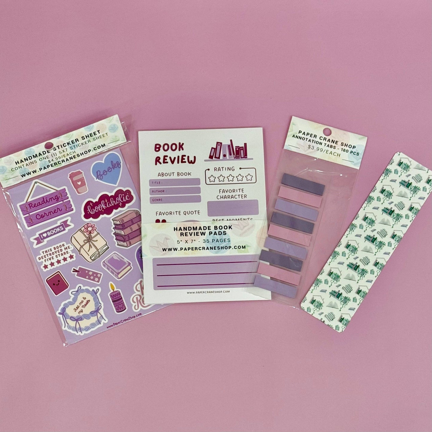 Collection of stationery items including a sticker sheet, book review pad, and bookmarks on a pink background.