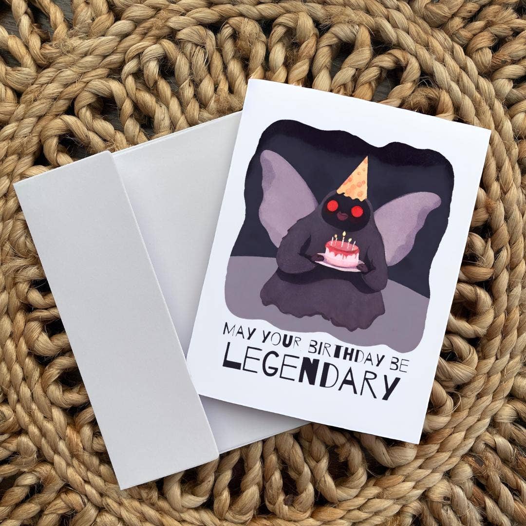 Birthday card with Mothman illustration and 'May your birthday be legendary' text on a textured surface.