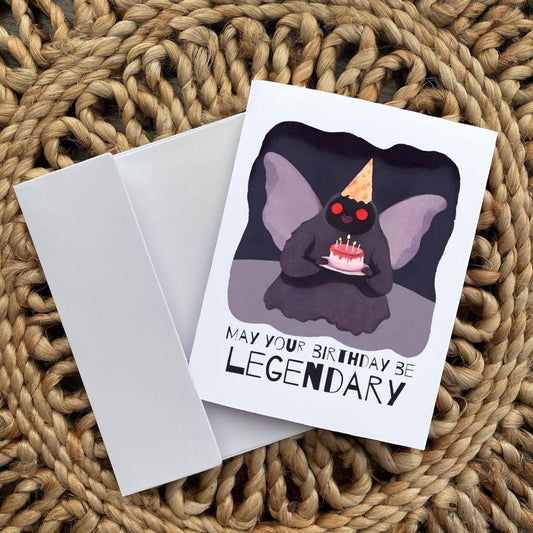 Birthday card with Mothman illustration and 'May your birthday be legendary' text on a textured surface.