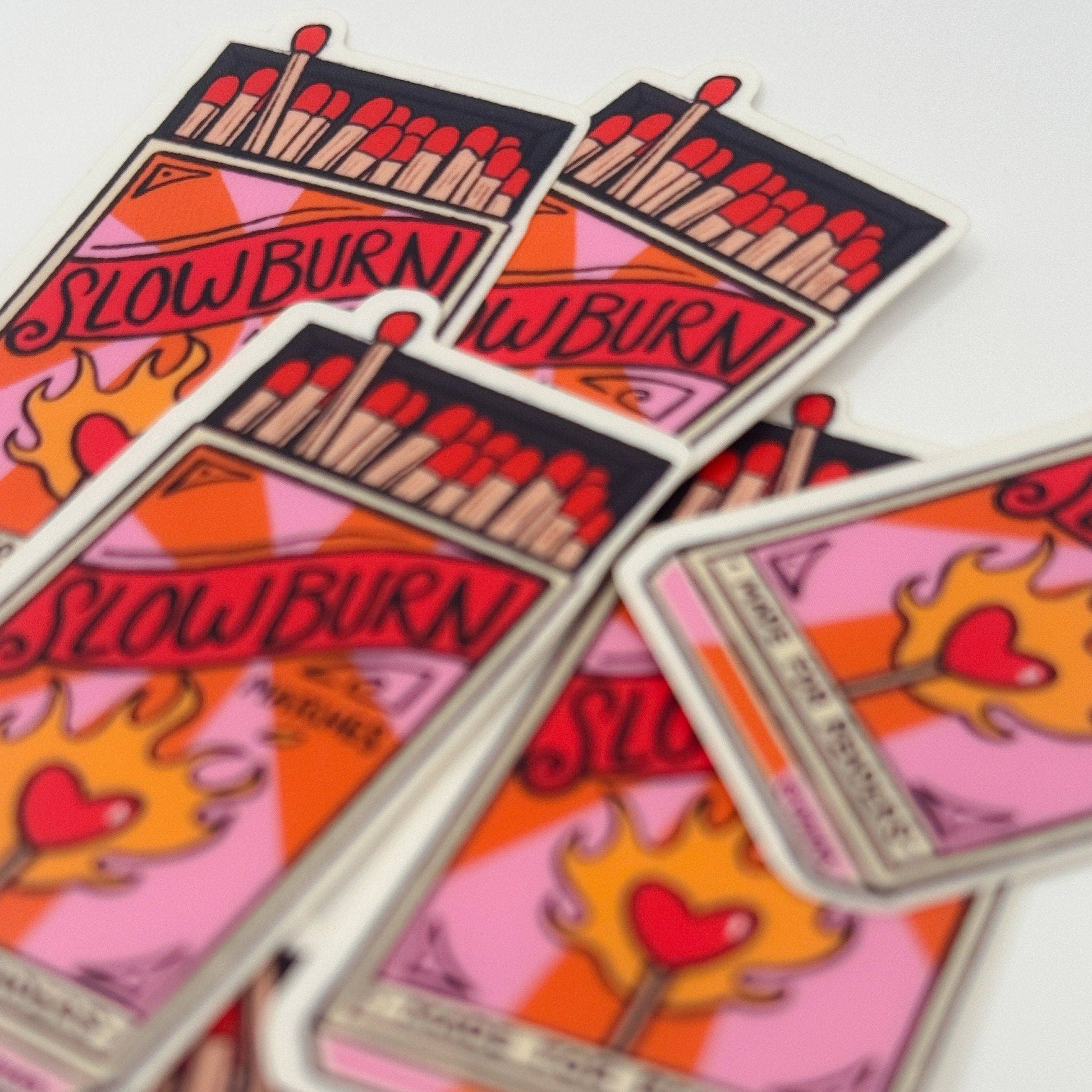 Colorful playing cards with matches and 'Slow Burn' text on a white background