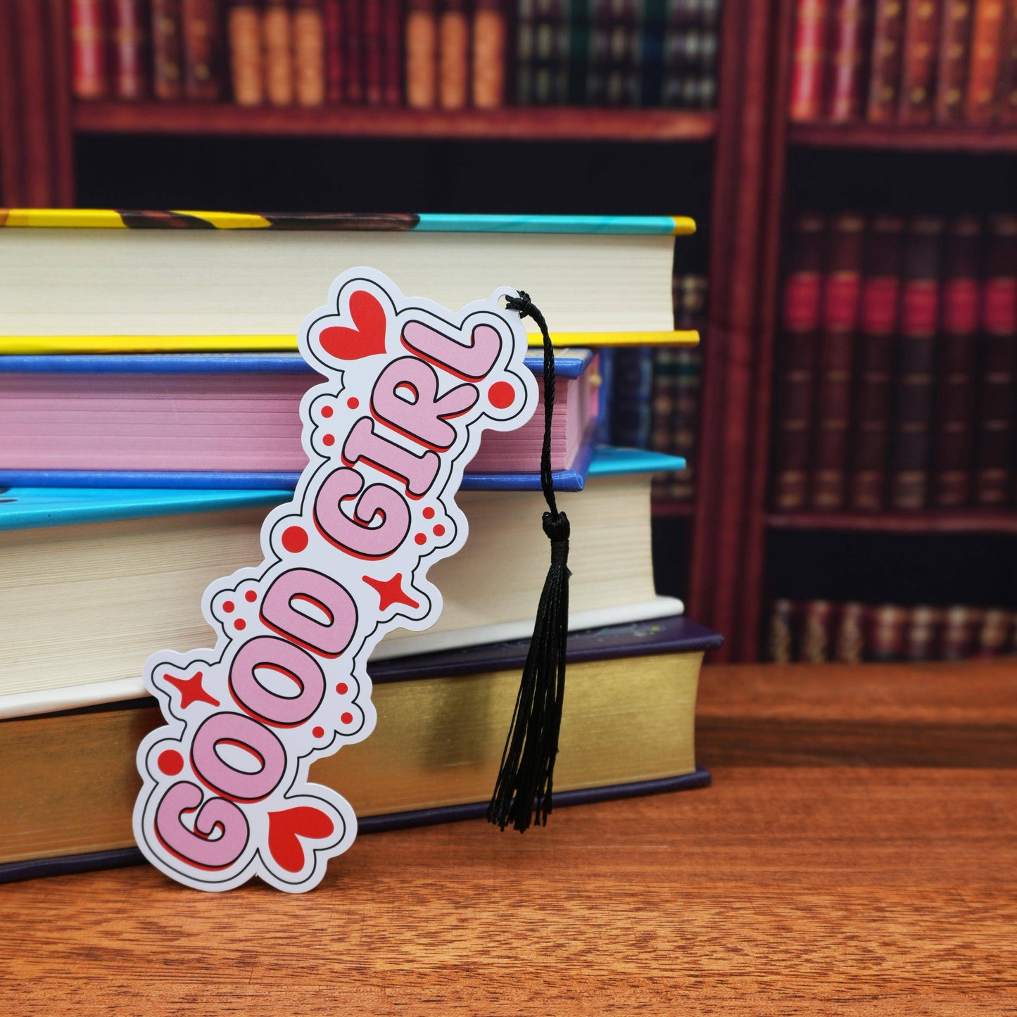 Bookmark with 'Good Girl' design on books with a bookshelf background