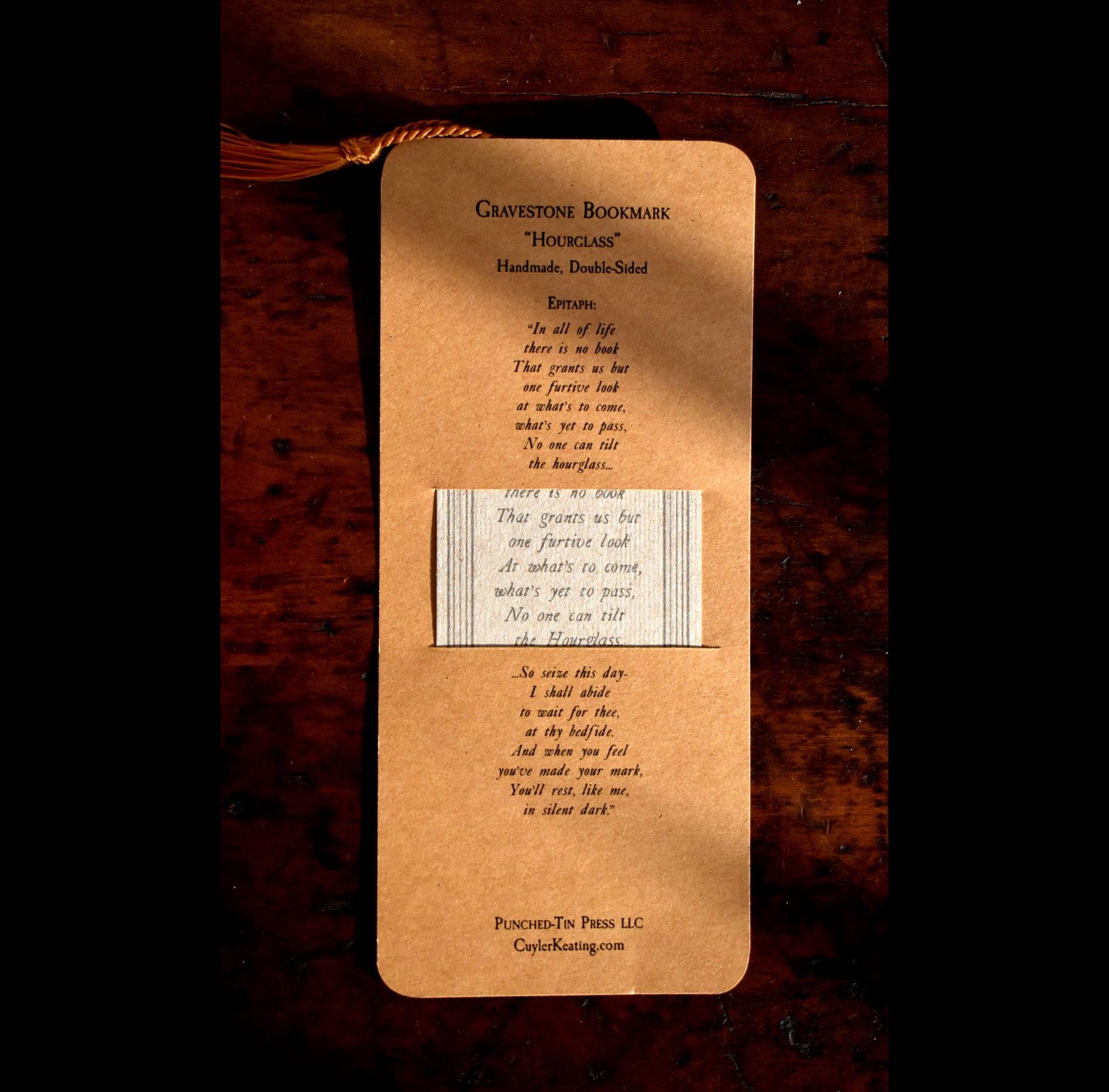 Brown gravestone bookmark with text on a wooden surface