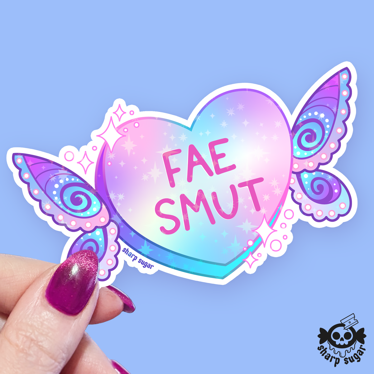 A heart-shaped sticker with butterfly wings and the text 'FAE SMUT' in pink, held by a hand with glittery purple fingernails against a light blue background. A 'sharp sugar' brand logo is visible in the bottom right corner.