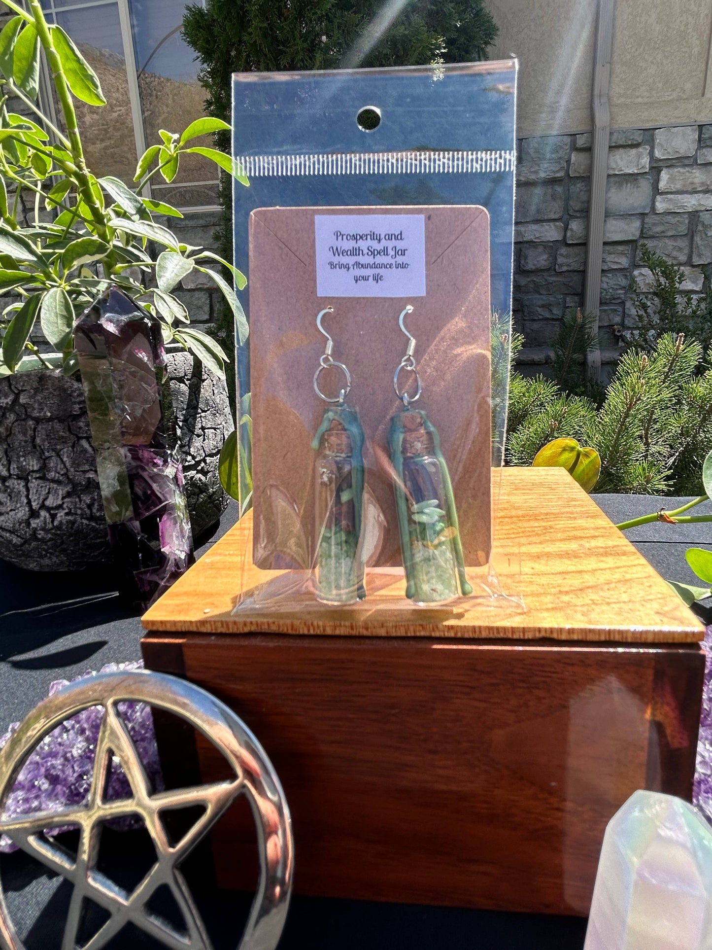 Earrings in packaging on a wooden stand with crystals and plants in the background