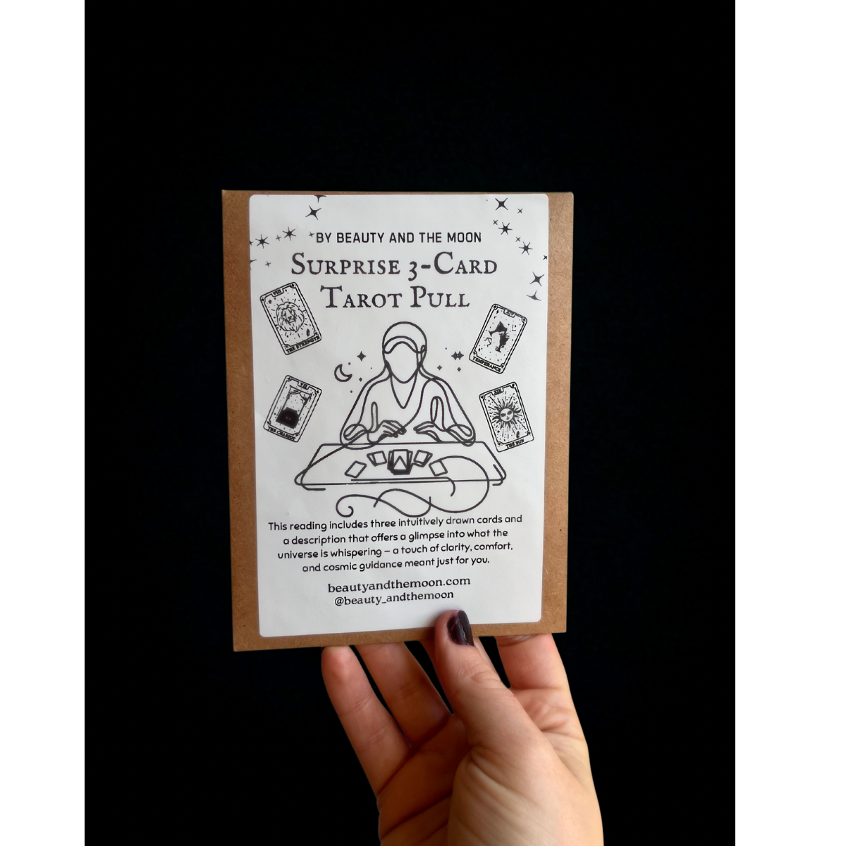Card with tarot design and text held by a hand against a black background